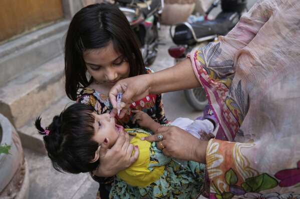 A health worker administers a polio vaccine to a child at a neighbourhood, in Lahore, Pakistan, Monday, May 26, 2025. (AP Photo/K.M. Chaudary)