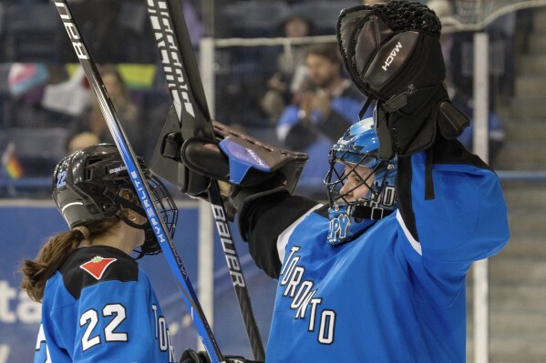 Toronto goaltender Kristen Campbell (50) celebrates clinching first place in the league with teammate Maggie Connors (22) after defeating Minnesota in a PWHL hockey game in Toronto on Wednesday, May 1, 2024. (Frank Gunn/The Canadian Press via AP)
