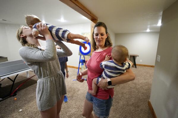 Fourteen-year-old Abby Visser holds her embryo-adopted brother and Amanda Visser holds her embryo-adopted six-month-old son at their home, Monday, May 13, 2024, in Sterling, Colorado. When faced with infertility, Christians who believe life begins at or around conception wrestle with the ethics of IVF and how to build a family in a way that conforms with their beliefs. (AP Photo/Jack Dempsey)