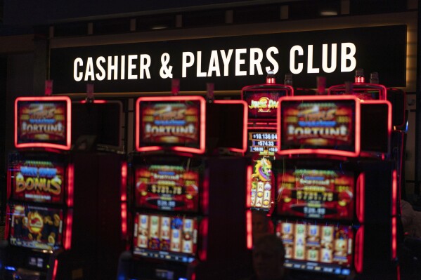A sign directing bettors to a cashier is displayed above electronic gaming machines at Turfway Park Racing & Gaming, Friday, Dec. 22, 2023, in Florence, Ky. The firing of Los Angeles Dodgers star Shohei Ohtani's interpreter and close friend after allegations of illegal gambling and theft from the Japanese baseball player is shining renewed attention on compulsive gambling. The National Council on Problem Gambling describes it as gambling that is damaging to a person or their family, often disrupting their daily life and career. (AP Photo/Carolyn Kaster)
