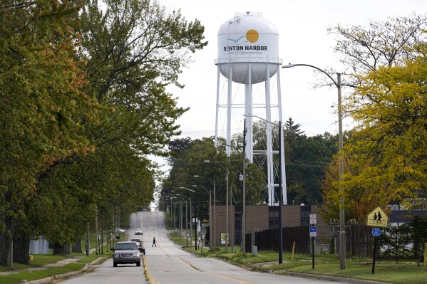 FILE - A lone resident of Benton Harbor, Mich., walks across Britain Street Friday, Oct. 22, 2021, near the city's water tower in Benton Harbor. Officials say health risks due to high lead levels in drinking water in the majority Black and impoverished Michigan city were not taken quickly to U.S. Environmental Protection Agency leadership. The EPA Office of Inspector General said in a report Thursday, Sept. 7, 2023 that staff monitoring the state’s response to lead levels in Benton Harbor failed to elevate the issue to the city’s residents. (AP Photo/Charles Rex Arbogast, File)
