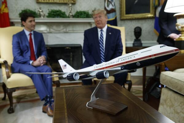 FILE - A model of the new Air Force One design sits on a table during a meeting between President Donald Trump and Canadian Prime Minister Justin Trudeau in the Oval Office of the White House, June 20, 2019, in Washington. President Joe Biden's administration has scrapped former President Trump's red, white and blue design for the new generation of presidential aircraft after an Air Force review suggested it would raise costs and delay the delivery of the new jets. (AP Photo/Evan Vucci, File)