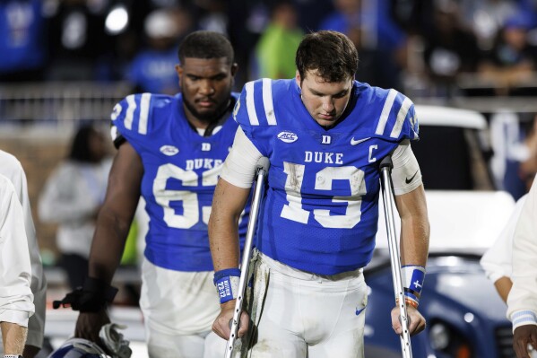 Duke quarterback Riley Leonard (13) leaves the field on crutches ahead of Jacob Monk (63) following a loss to Notre Dame in an NCAA college football game in Durham, N.C., Saturday, Sept. 30, 2023. (AP Photo/Ben McKeown)