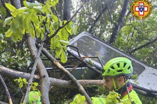 In this photo released by the Italian Alpine and Speleological Rescue Corps on Thursday, April 17, 2025, rescuers reach for the smashed gondola of the Mt. Faito cable car near Naples in southern Italy.