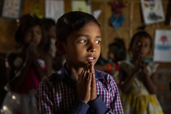 Imradul Ali, 10, prays with others in a classroom in a school near a landfill on the outskirts of Gauhati, India, Friday, Feb. 5, 2021. Once school is done for the day, Ali, rushes home to change out of his uniform so that he can start his job as a scavenger in India’s remote northeast. Coming from a family of scavengers or “rag pickers," Ali started doing it over a year ago to help his family make more money. Ali says he doesn’t want to spend his life doing this, but he doesn’t know what the future holds. (AP Photo/Anupam Nath)