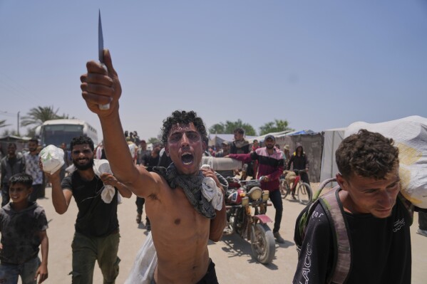 A Palestinian shouts to the camera in Arabic, "We get food with the taste of death and blood," as he carries a bag containing food and humanitarian aid packages delivered by the Gaza Humanitarian Foundation, a U.S.-backed organization, in Rafah, southern Gaza Strip, Tuesday, June 10, 2025. (AP Photo/Abdel Kareem Hana, File)