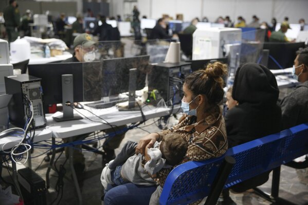 Migrant families wait to be questioned at the preliminary intake area of the Donna Department of Homeland Security holding facility, the main detention center for unaccompanied children in the Rio Grande Valley, in Donna, Texas, Tuesday, March 30, 2021. (AP Photo/Dario Lopez-Mills, Pool)