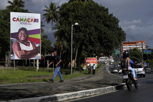 A person walks near a sign for Camacari, Bahia state, Brazil, Friday, March 7, 2025. (AP Photo/Eraldo Peres)