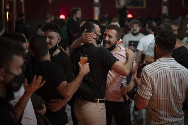 People greet each other before a concert in Barcelona, Spain, Saturday, Dec. 12, 2020. Eager for a live music show after months of social distancing, more than 1,000 Barcelona residents gathered Saturday to participate in a medical study to evaluate the effectiveness of same-day coronavirus screening to safely hold cultural events. After passing an antigen screening, 500 of the volunteers were randomly selected to enjoy a free concert inside Barcelona's Apolo Theater. (AP Photo/Emilio Morenatti)