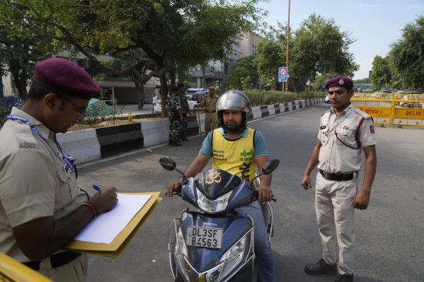 A policeman takes down details of a scooterist entering into a restricted zone ahead of this week G 20 Summit, in New Delhi, India, Friday, Sept. 8, 2023. (AP Photo/Manish Swarup)