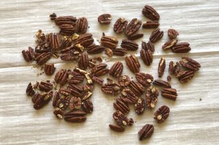 This January 17, 2020 photo shows toasted pecans resting on parchment paper in Amagansett, N.Y. Toasting nuts enhances their flavor and removes all the raw green, slightly astringent flavors that you taste when they are uncooked. (Elizabeth Karmel via AP)