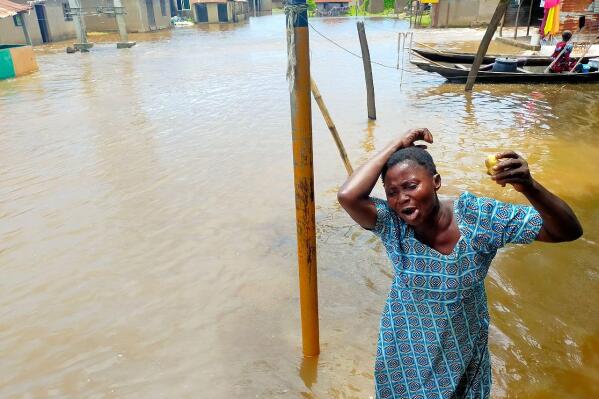 In this photo released by National Emergency Management Agency, a woman cries as she stand on a flooded street following a boat accident in Anambra, Nigeria, Friday, Oct. 7, 2022. Seventy-six people are missing after a boat capsized in a flooded community in Nigeria's southeast Anambra state, emergency officials told the Associated Press on Monday. (National Emergency Management Agency via AP)