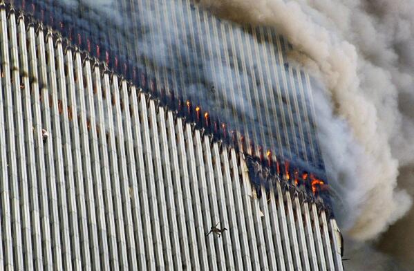 A person falls from the north tower of New York's World Trade Center as another clings to the outside, left, while smoke and fire billow from the building, Tuesday Sept. 11, 2001. (AP Photo/Richard Drew)
