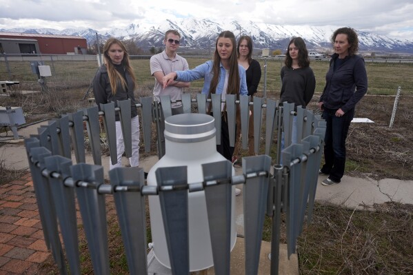 Lydia Conger, from left, all of Utah State University, Casey Olson, climate data analyst, Ashley Lewis and Maya Cottam stand with Kaitlyn Linford, high school student and her mother, Cherisse Linford, while being shown a wind-shielded precipitation gauge during a tour on April 1, 2024, in Logan, Utah. Increasingly, U.S. universities are creating climate change programs to meet demand from students who want to apply their firsthand experience to what they do after high school. (AP Photo/Rick Bowmer)