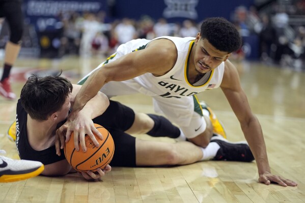 Baylor guard RayJ Dennis, top, tries to steal the ball from Cincinnati guard Simas Lukosius during the first half of an NCAA college basketball game in the quarterfinal round of the Big 12 Conference tournament, Thursday, March 14, 2024, in Kansas City, Mo. (AP Photo/Charlie Riedel)