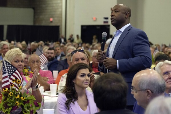 FILE - Republican presidential candidate Sen. Tim Scott, R-S.C., right, walks by Casey DeSantis, wife of GOP rival and Florida Gov. Ron DeSantis, center, as he speaks at Rep. Jeff Duncan's Faith & Freedom BBQ fundraiser, Aug. 28, 2023, in Anderson, S.C. Republicans are responding to a late summer spike in COVID-19 by raising familiar fears that government-issued lockdowns and mask mandates are on the horizon. GOP presidential hopefuls including Florida Gov. Ron DeSantis, South Carolina Sen. Tim Scott and former President Donald Trump have spread this narrative in the last week. (AP Photo/Meg Kinnard, File)