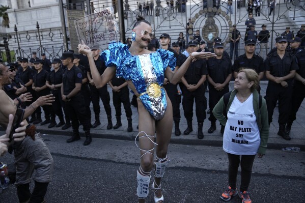 Vick Teker, dressed in a national flag outfit holding a sign with a message that reads in Spanish: 