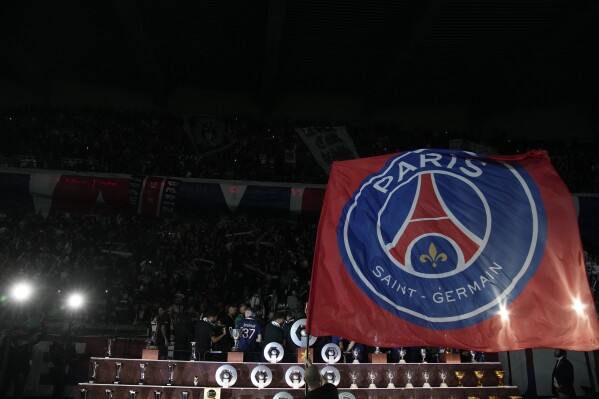 Paris Saint Germain flag is waved as players celebrate PSG's French League One title after the French League One soccer match between Paris Saint-Germain and Toulouse at the Parc des Princes stadium in Paris, Sunday, May 12, 2024. (AP Photo/Christophe Ena)