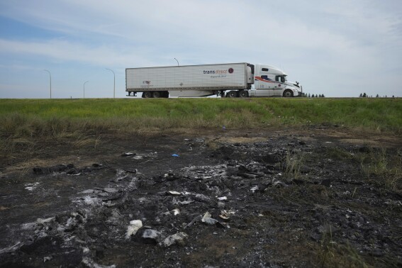 A patch of ground sits scorched where a bus carrying seniors to a casino ended up after colliding with a semi-trailer truck and burning on Thursday on the edge of the Trans-Canada Highway near Carberry, Manitoba, Friday, June 16, 2023. Police said 15 people were killed and 10 more were sent to hospital. (Darryl Dyck/The Canadian Press via AP)