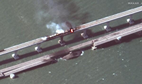 This satellite image provided by Maxar Technologies shows damage to the Kerch Bridge, which connects the Crimean Peninsula with Russia crossing a strait between the Black Sea and the Sea of Azov, and rail cars on fire on Saturday, Oct. 8, 2022. (Maxar Technologies via AP)