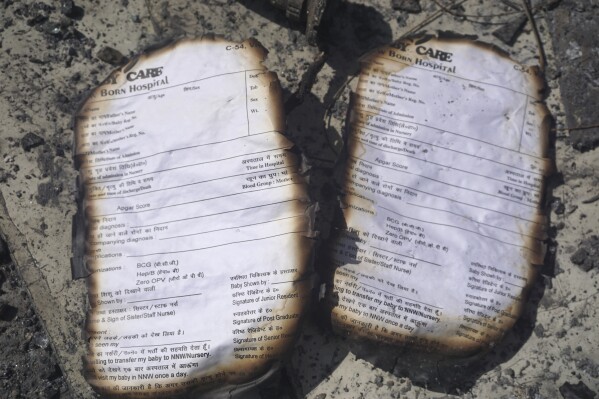Burnt registration cards lie on the floor of a baby care center in New Delhi, India, Sunday, May 26, 2024. A fire broke out in the care center on Saturday night killing six infants, a fire service officer said on Sunday. (AP Photo/Dinesh Joshi)