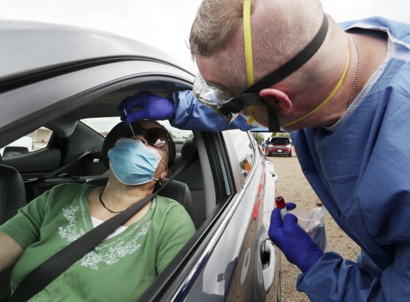 An Ohio National Guard Medic tests Elizabeth England in her car at a Summit County Department of Health COVID-19 testing site at Chapel Hill Mall on Saturday, Sept. 12, 2020, in Akron, Ohio. Hospitals around the United States are starting to buckle from a resurgence of COVID-19 cases, with several states setting records for the number of people hospitalized and leaders scrambling to find extra beds and staff. New highs in cases have been reported in states big and small, from Idaho to Ohio. (Mike Cardew/Akron Beacon Journal via AP)