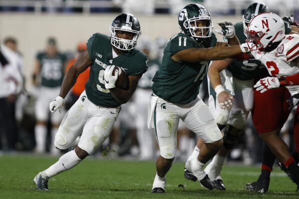 Michigan State's Kenneth Walker III, left, rushes against Nebraska's Caleb Tannor, right, as Michigan State's Connor Heyward (11) blocks during overtime of an NCAA college football game, Saturday, Sept. 25, 2021, in East Lansing, Mich. Michigan State won 23-20 in overtime. (AP Photo/Al Goldis)