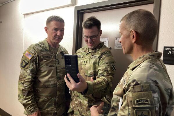 Army Chief of Staff Gen. James McConville, left, takes part in a cellphone conversation with Spc. Benjamin Soares, middle, and Sergeant Major of the Army Michael Grinston while visiting barracks in Fort Stewart, Ga., on Tuesday, March 7, 2023. (Russ Bynum/AP Photo)