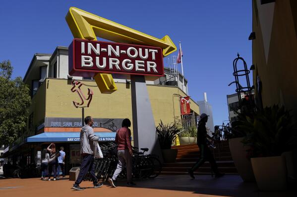 File - People walk below an In-N-Out Burger restaurant sign in San Francisco, Thursday, Aug. 25, 2022. The nation's employers kept hiring briskly in November despite high inflation and a slow-growing economy. Much of the growth came in education and health care, and a category made up mostly of restaurants, hotels, and entertainment firms. (AP Photo/Jeff Chiu, File)