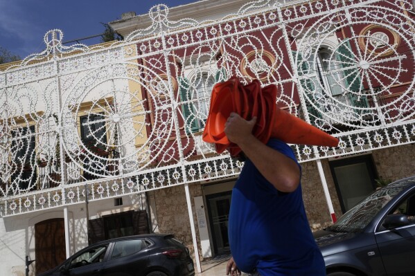 Workers give the last touch to the illumination set for the Patron Saint feast in Fasano, near Borgo Egnazia, southern Italy, Wednesday, June 12, 2024. A Group of Seven summit aiming to consolidate support for Ukraine opens Thursday under a vastly different political landscape than even a few days ago, after European Parliament elections jolted the leaders of France and Germany and emboldened Italian Premier Giorgia Meloni. (AP Photo/Gregorio Borgia)