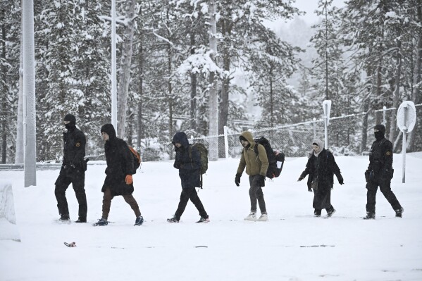 Finnish border guards escort migrants arriving at the Radja Joseppi border crossing between Russia and Finland in Inari, northern Finland, Saturday, November 25, 2023. The European Union's border protection agency said it would deploy dozens of police officers and equipment. Russia has sent reinforcements to Finland to help with border security amid suspicions that Russia is behind the influx of migrants into Finland.  (Emi Korhonen/Retikva, via AP)