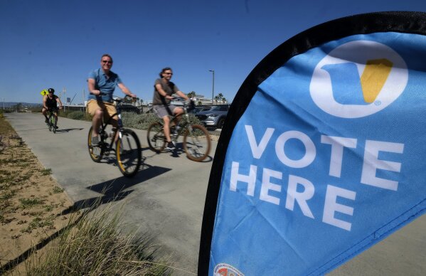 Bikers ride past a voting center on the Super Tuesday, in El Segundo, Calif., Tuesday, March 3, 2020. (AP Photo/Ringo H.W. Chiu)