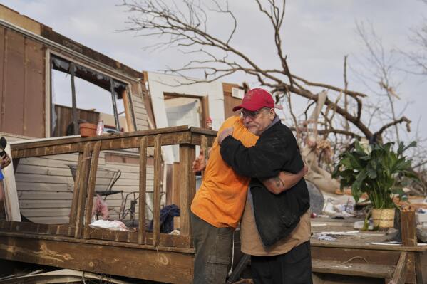 Tim Scott, right, gets a hug from friend Jorden Harris outside Scott's home he was inside when it was destroyed during a severe storm the evening before Saturday, March 15, 2025, in Wayne County, Mo. (AP Photo/Jeff Roberson)