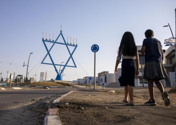 Girls walk in a new neighborhood that is under construction in Sderot, Israel, July 20, 2021. No place in Israel has been hit harder by Palestinian rocket fire than Sderot, a working-class town just about a mile (1.5 kilometers) from the Gaza border. Although Sderot is enjoying an economic boom and revival, a generation of children and parents are suffering from the traumatic effects of two decades of rocket fire that experts are still struggling to understand. (AP Photo/Ariel Schalit)