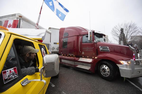 A person in a pickup truck and trailer blocking Wellington Street watches as a semi-trailer truck drives away, during an ongoing protest against COVID-19 measures that has grown into a broader anti-government protest, in Ottawa, Ontario, on Thursday, Feb. 17, 2022. (Justin Tang/The Canadian Press via AP)