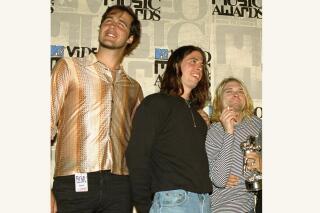 FILE - Nirvana band members Krist Novoselic, from left, Dave Grohl and Kurt Cobain pose after receiving the award for best alternative video for "In Bloom" at the 10th annual MTV Video Music Awards on Sept. 2, 1993, in Universal City, Calif. A 30-year-old man who appeared nude at 4 months old in 1991 on the cover of Nirvana's "Nevermind" album is suing the band and others, alleging the image is child pornography they have profited from. The suit, filed by Spencer Elden on Tuesday, Aug 24, 2021, seeks at least $150,000 from each of more than a dozen defendants, including the Kurt Cobain estate, surviving Nirvana members Novocelic and Grohl and Geffen Records. (AP Photo/Mark J. Terrill, File)