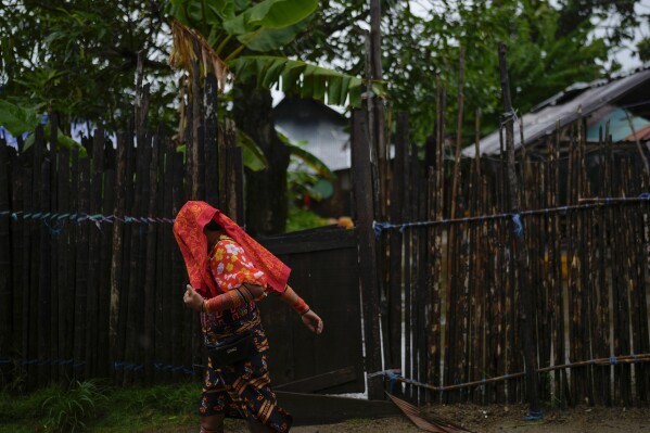 A Guna Indigenous woman covers her head due to light rain on Gardi Sugdub Island, part of the San Blas archipelago off Panama's Caribbean coast, Saturday, May 25, 2024. Due to rising sea levels, about 300 Guna Indigenous families will relocate to new homes, built by the government, on the mainland. (AP Photo/Matias Delacroix)