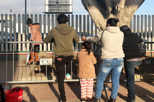 In this Wednesday, Jan. 8, 2020, photo, people seeking asylum in the United States wait at the border crossing bridge in Tijuana, Mexico, just across the border from San Diego. The number of people arrested or stopped entering the U.S. along the Mexico border fell for a seventh straight month in December, with Mexicans making up a larger than usual part of the mix, authorities said Thursday. (AP Photo/Elliot Spagat)