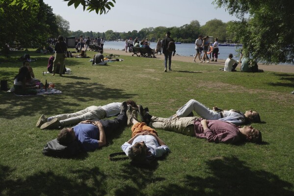 FILE - People enjoy the sunny weather at a park in London, May 27, 2023. The British economy unexpectedly grew in the second quarter of the year largely as a result of a strong rebound in June when many businesses, particularly in the leisure sector benefited from the warm and settled weather, official figures showed Friday Aug. 11, 2023. (AP Photo/Kin Cheung, File)