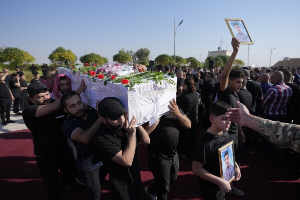 Friends and relatives attend a funeral for the victims who died in a fire during a wedding ceremony in Hamdaniya, Iraq, Friday, Sept. 29, 2023. A fire that raced through a hall hosting a Christian wedding in northern Iraq killed multiple people, authorities said. (AP Photo/Hadi Mizban)