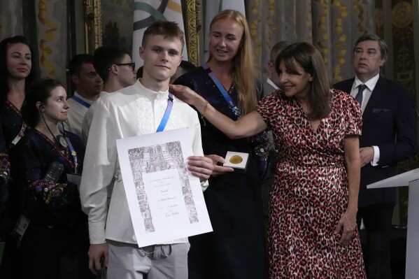 Paris mayor Anne Hidalgo, right, awards Ukrainian athletes Oleskii Sereda and Anastasiia Kozhenkova, center, during a ceremony at the 2024 Summer Olympics, Thursday, Aug. 1, 2024, in Paris, France. Hidalgo awarded the whole Ukrainian delegation with the Medal of the City of Paris. (AP Photo/Michel Euler)