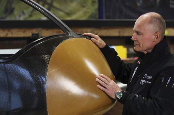 Swiss aviation pioneer Bertrand Piccard touches Climate Impulse, a plane powered by liquid hydrogen, at the press presentation of the project in a hangar in Les Sables d'Olonne, France, Thursday, Feb. 13, 2025. (AP Photo/Yohan Bonnet)