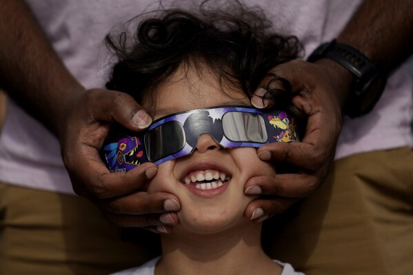 FILE - Viewers use special glasses to watch from San Antonio, as the moon moves in front of the sun during an annular solar eclipse, or ring of fire, Oct. 14, 2023. The total solar eclipse on April 8, 2024 may be weeks away but businesses are ready for the celestial event with oodles of special eclipse glasses for sale, along with T-shirts and other souvenirs. (AP Photo/Eric Gay, File)