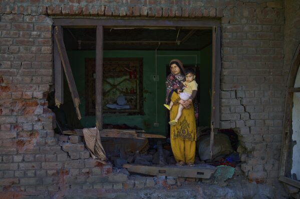 Nimarak holds her child as she inspects her house damaged by artillery shelling from Pakistan, in the border village of Gingal, north of Srinagar, Indian-controlled Kashmir, May 14, 2025. (AP Photo/Dar Yasin)