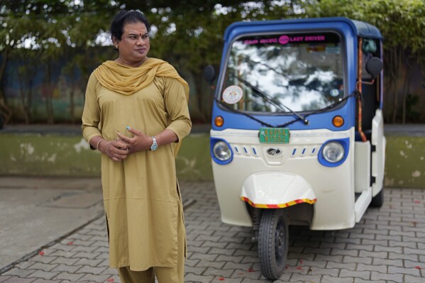 Preethi, a 38-year-old transgender woman who uses only her first name, stands next to her electric auto rickshaw as she speaks to The Associated Press in Bengaluru, India, Monday, July 10, 2023. She's now one of millions of electric vehicle owners in India, but one of very few to have received an EV through a charitable donation. (AP Photo/Aijaz Rahi)