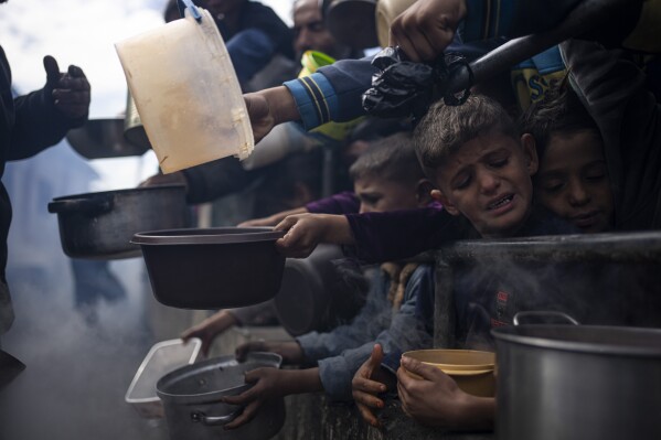 Palestinians line up for a meal in Rafah, Gaza Strip, Friday, Feb. 16, 2024. International aid agencies say Gaza is suffering from shortages of food, medicine and other basic supplies as a result of the war between Israel and Hamas. (AP Photo/Fatima Shbair)