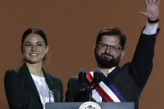 FILE - Chile's new President Gabriel Boric, accompanied by first lady Irina Karamanos, waves to supporters after delivering a speech from a balcony of La Moneda presidential palace, in Santiago, Chile, March 11, 2022. Chile's new left-leaning government is doing away with the office of the first lady as part of its effort to transform a role that both the president and his partner have characterized as archaic. The government said Wednesday, June 22, 2022, that first lady Irina Karamanos will now be known as the “sociocultural coordinator of the republic’s presidency.” (AP Photo/Esteban Felix, File)