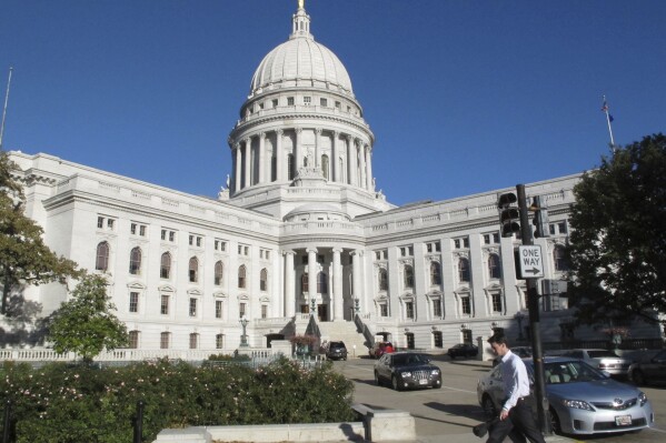 FILE - A man walks by the Wisconsin Capitol, Oct. 10, 2012, in Madison, Wis. Wisconsin Republicans urged the state Supreme Court on Thursday, Feb. 8, 2024, to ignore a report from redistricting consultants that determined GOP proposed legislative maps were unconstitutional partisan gerrymanders. (AP Photo/Scott Bauer, File)