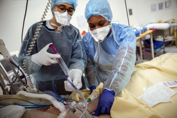 Nurses Nadia Boudra, left, and Yvana Faro, right, care for a patient inside an operating room now used for unconscious COVID-19 patients at Bichat Hospital, AP-HP, in Paris, Thursday, April 22, 2021. France still had nearly 6,000 critically ill patients in ICUs this week as the government embarked on the perilous process of gingerly easing the country out of its latest lockdown, too prematurely for those on pandemic frontlines in hospitals. President Emmanuel Macron's decision to reopen elementary schools on Monday and allow people to move about more freely again in May, even though ICU numbers have remained stubbornly higher than at any point since the pandemic's catastrophic first wave, marks another shift in multiple European capitals away from prioritizing hospitals. (AP Photo/Lewis Joly)