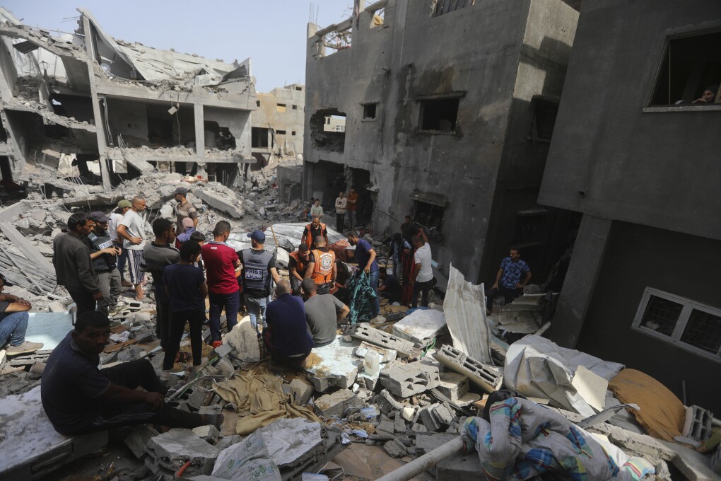 Palestinians look at the destruction after an Israeli strike on a residential building in Nuseirat Refugee Camp, Gaza Strip, Sunday, May 19, 2024. (AP Photo/Ismael Abu Dayyah)